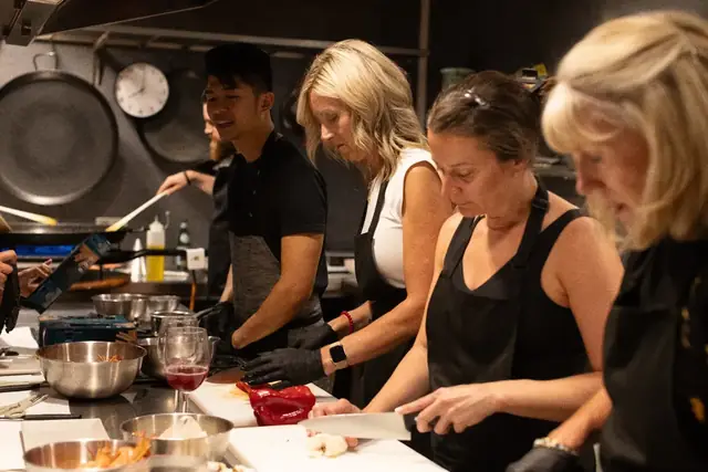 Guests chopping and stirring together in the cooking class kitchen