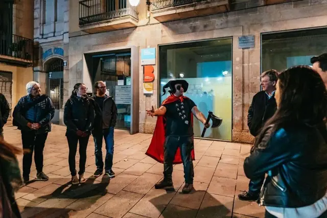 A guide in costume telling a story to the group at night
